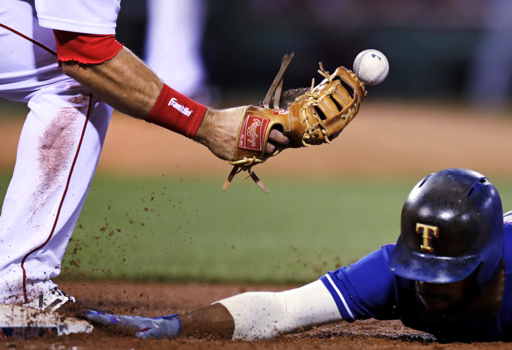 The ball bounces away from Boston Red Sox first baseman Mitch Moreland, left, while trying to unsuccessfully make a pick-off tag on Texas runner Delino DeShields during the fifth inning Tuesday.