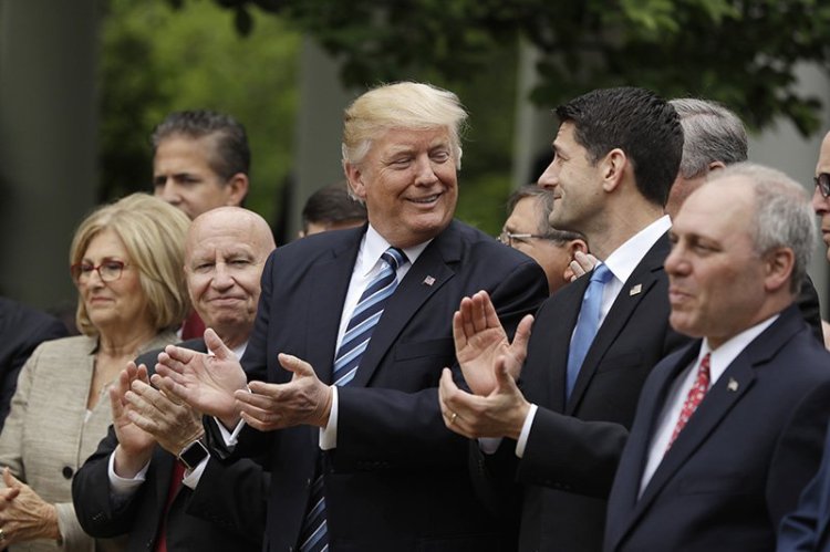 President Donald Trump, flanked by House Ways and Means Committee Chairman Rep. Kevin Brady, R-Texas, and House Speaker Paul Ryan of Wis. applaud in the Rose Garden of the White House after the passage of the health care bill. 