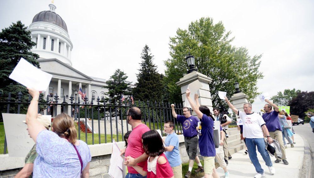 Maine state employees union members march past the State House on Saturday, protesting the shutdown that went into effect at 12:01 a.m.