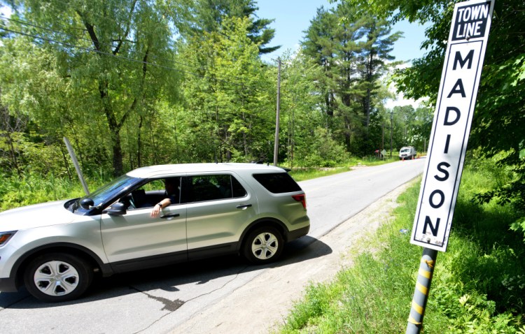 A Maine State Police trooper turns vehicles around Wednesday on Russell Road at the town line separating Skowhegan and Madison as investigators work at the scene of four fatal shootings.