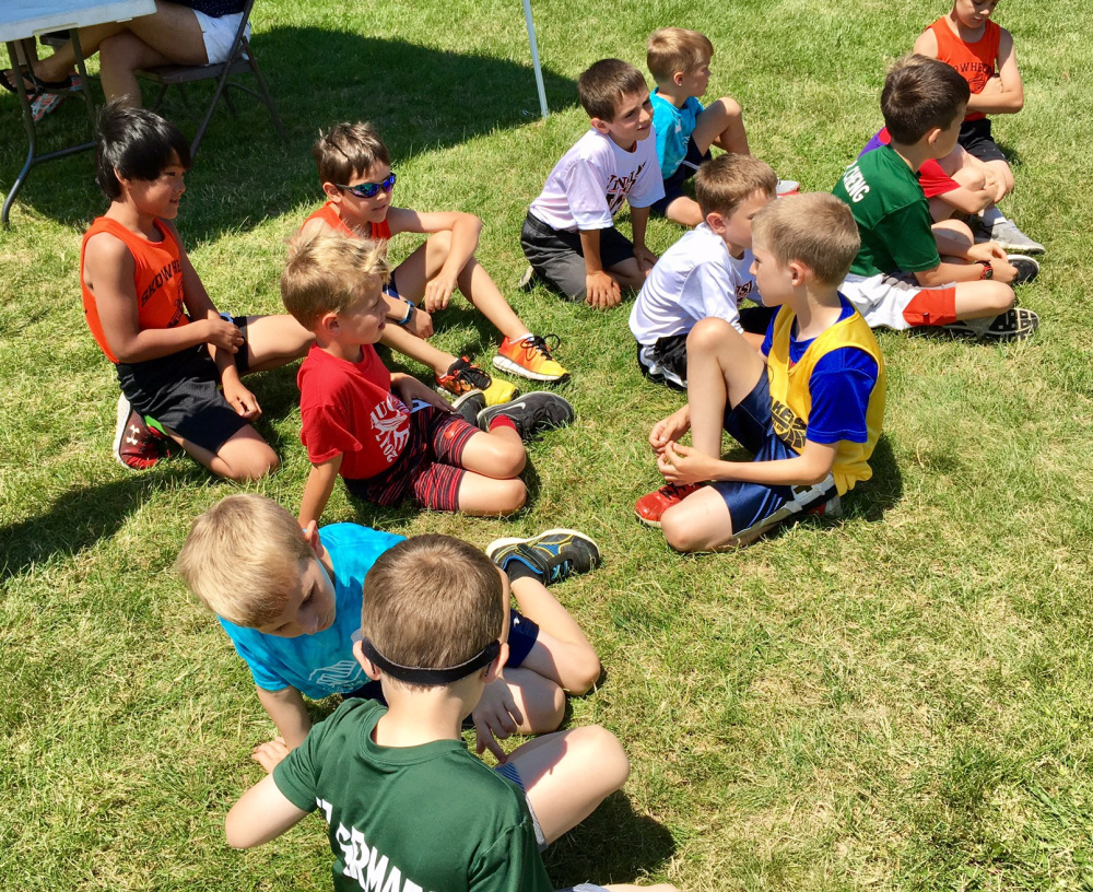 Boys wait in the infield for their group to be called for the 8 and under 400 meters on Thursday at Winslow High School.