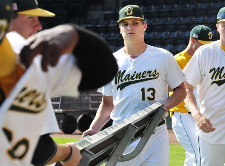 Former Messalonskee star Jake Dexter helps carry a bench onto the Goodall Park field Wednesday in Sanford. Dexter pitches for the Sanford Mainers.