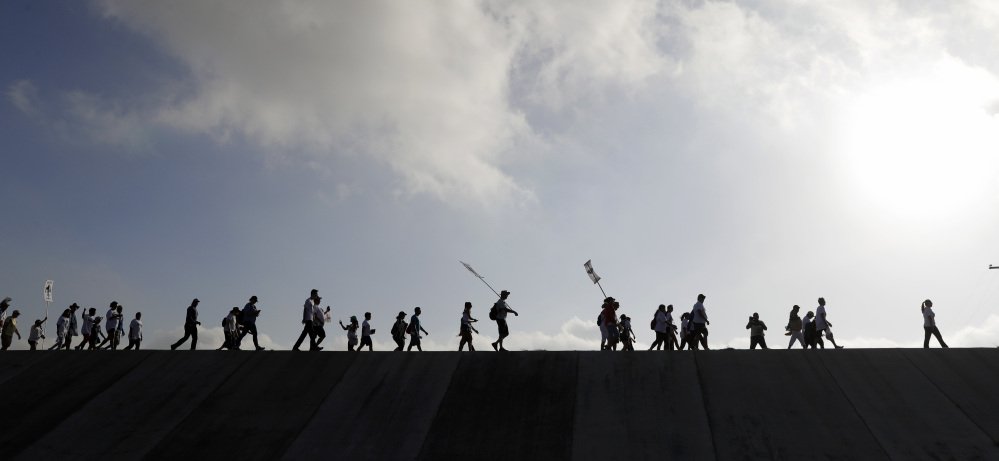 Hundreds of people march along a levee in South Texas toward the Rio Grande to oppose the wall that President Trump wants to build on the river.