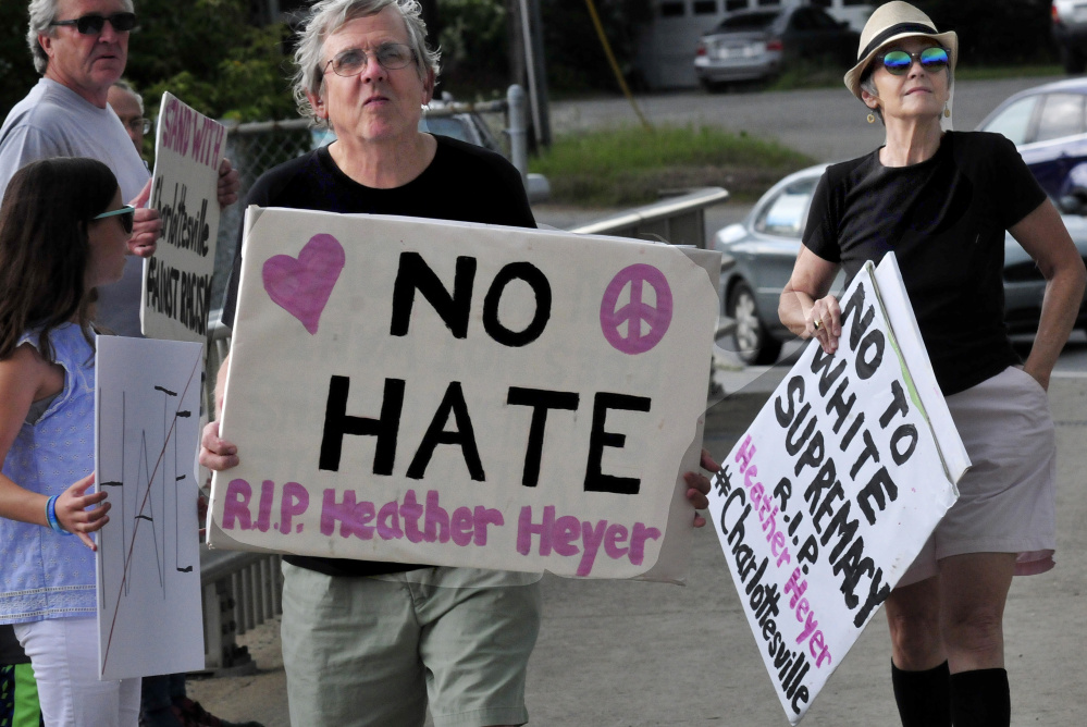 Mark Roman and Lisa Savage hold signs among protesters with Stand With Charlottesville Against White Supremacy during an anti-racist rally in Skowhegfan on Sunday.