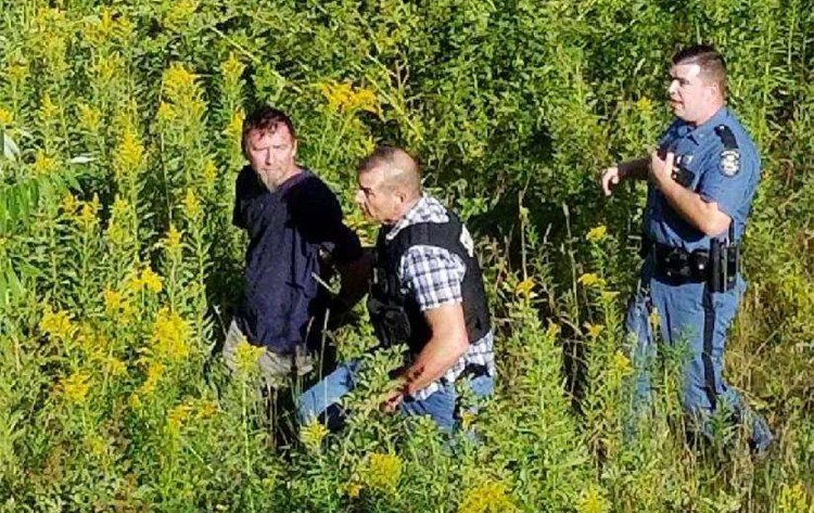 State Troopers David Alexander and John Darcy
taking 48 year old Glen Brackett of Biddeford out of the woods following his arrest yesterday on bank robbery charges.