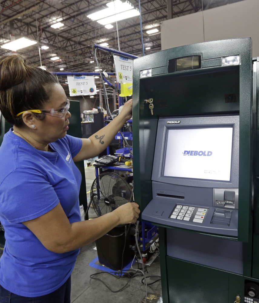 A Diebold Nixdorf worker installs software in a new version of ATMs, some of which act more like smart devices with swiping and other features.