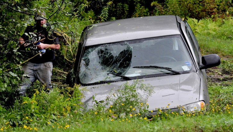 A man throws belongings back into a truck that crashed off the Norridgewock Road in Fairfield on Wednesday. The accident brought police, firefighters and an ambulance to the scene.