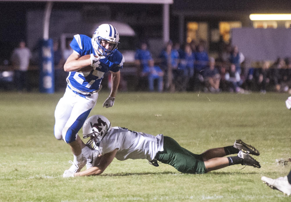 Madison senior Sean Whalen (27) gets wrapped up by Winthrop/Monmouth defender Cameron Gaghan during a recent game at Rudman Field in Madison. The Bulldogs play Old Orchard Beach on Friday.