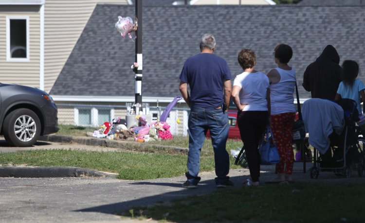 Neighbors stand by a memorial at Pleasant View Acres for 17 month-old Tiannah Sevey who died Saturday when her mother, Taneisha Thomas, ran over her. 