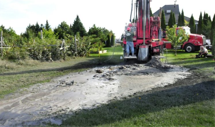 Chad Grignon, of Pine State Drilling, retracts drill pipes after hitting water Sept. 25 beside the Palermo Community Garden.