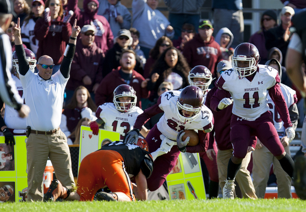 Maine Central Institute's Will Russell pushes for extra yards as Winslow's defense goes for the stop during a Class C North semifinal game Saturday at Poulin Field in Winslow.