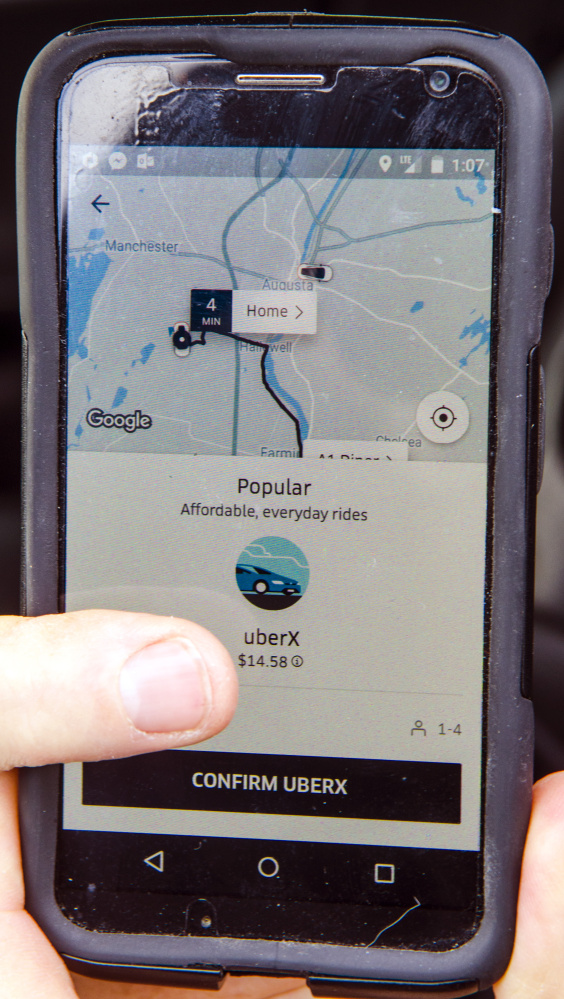 Scott Cowger holds up his phone with the Uber app on it Wednesday in his Tesla in Hallowell.