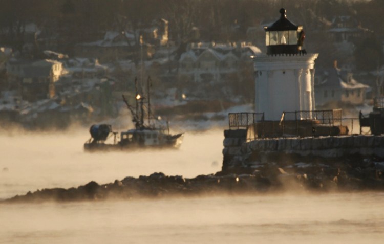 A fishing vessel motors through sea smoke, past Bug Light on Wednesday morning.