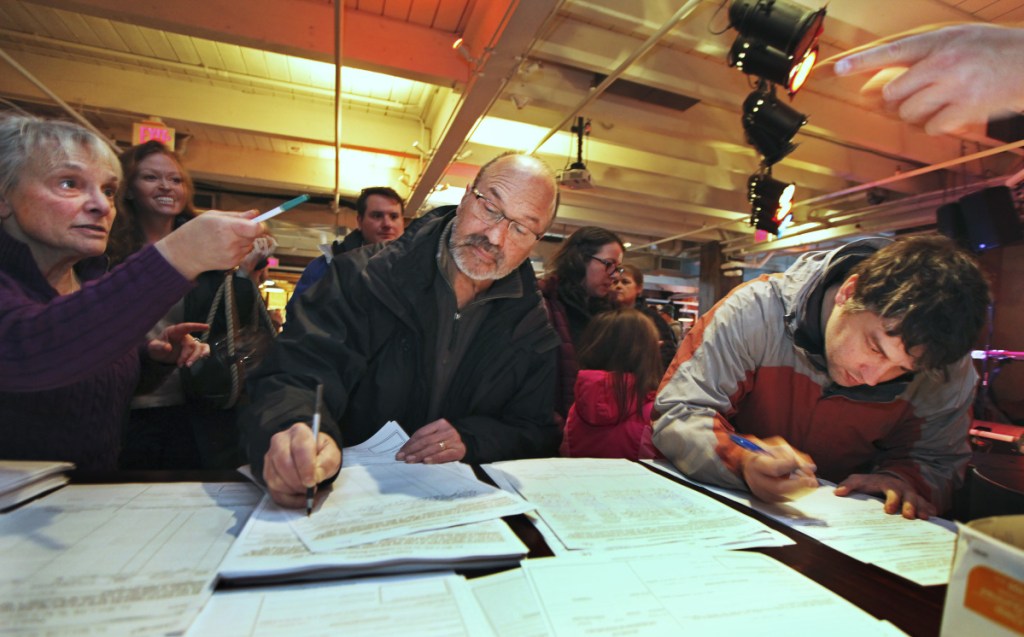 Ray Wingert of Gorham, center, and Stephen Pisani of Lyman, right, add their names to the people's veto referendum petition as notary Rosemarie DeAngelis witnesses. The 250 signatures added Sunday brings the total so far to 55,000.