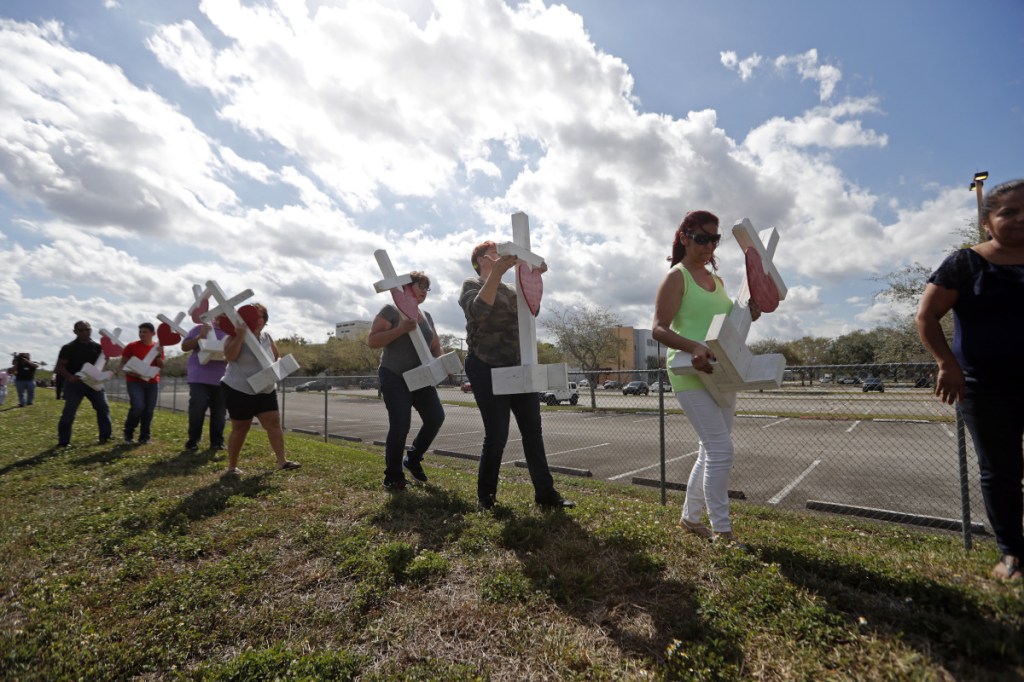 Volunteers carry 17 crosses to be placed outside the Marjory Stoneman Douglas High School in Parkland, Fla., where 17 people were killed in a mass shooting.