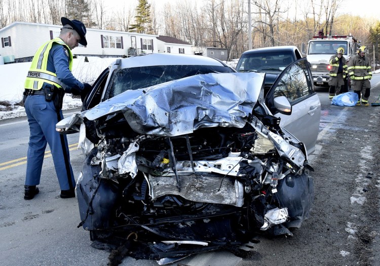 Trooper Jacob Roddy gathers evidence from a demolished vehicle involved in an accident with a truck, background, on West River Road in Sidney on Monday. The roadway was blocked.