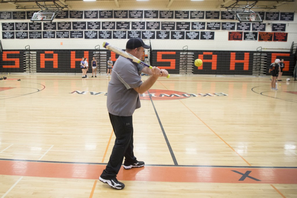 Volunteer softball coach John Alward hits ground balls to infielders during an April 3 practice at Skowhegan Area High School.