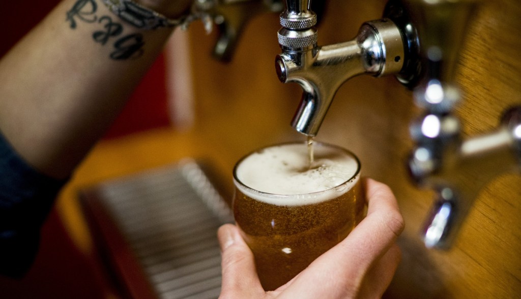 Danielle Coons pours a glass of beer at D.L. Geary Brewing Co. in Portland in 2017. Under new owners, the Maine craft brewer is now ranked No. 9 in production.