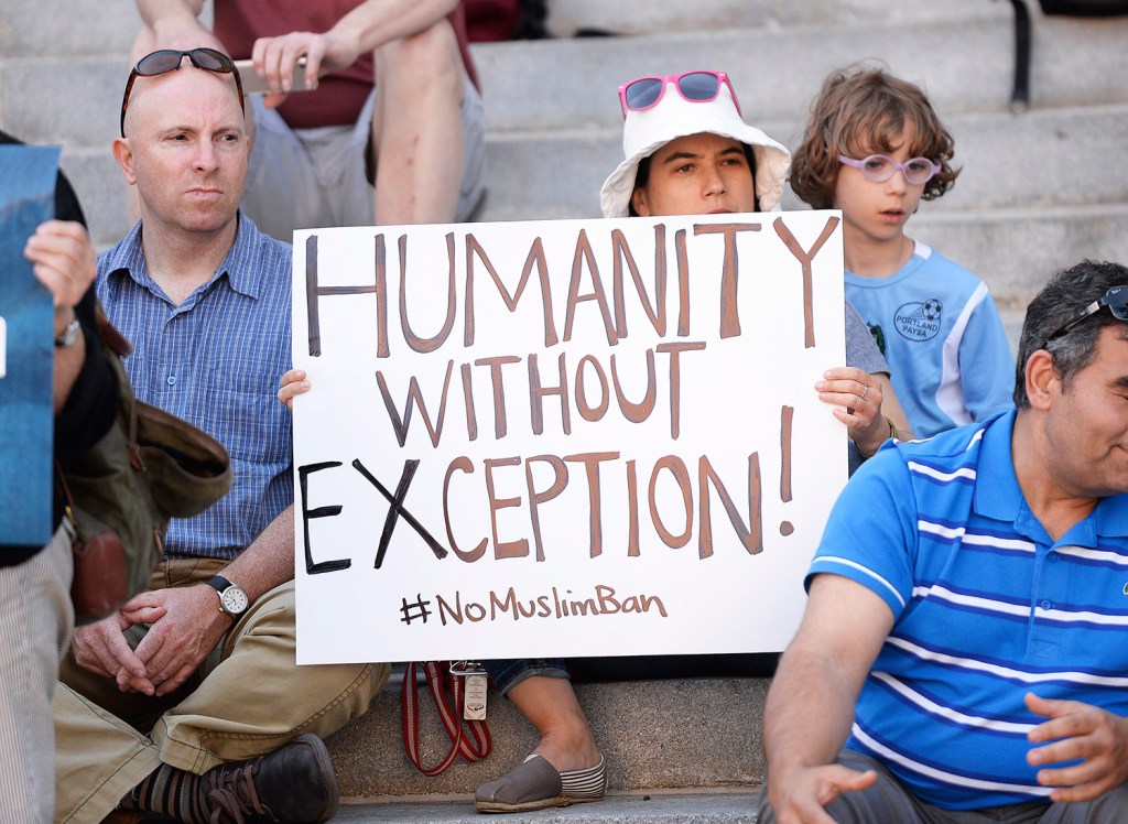 Protesters, left to right, John Thibodeau and Joanna Frankel and her son Elijah Brody, 9, of Portland participate in the Stand with Muslims rally Tuesday evening at Portland City Hall.