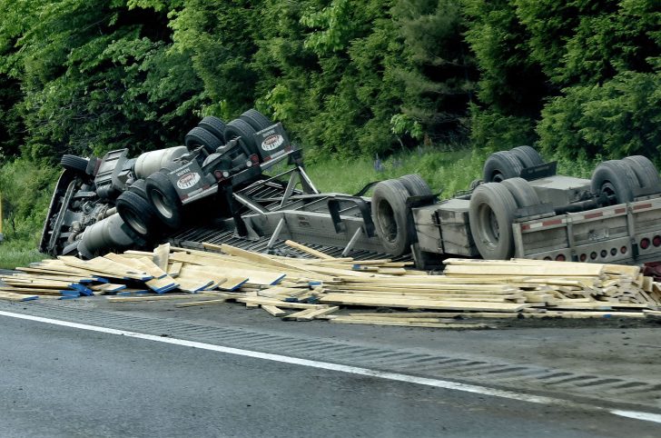 First responders wait for police to reconstruct the scene of a tractor-trailer rollover Monday on the southbound side of I-95 in Sidney. The truck was loaded with lumber.