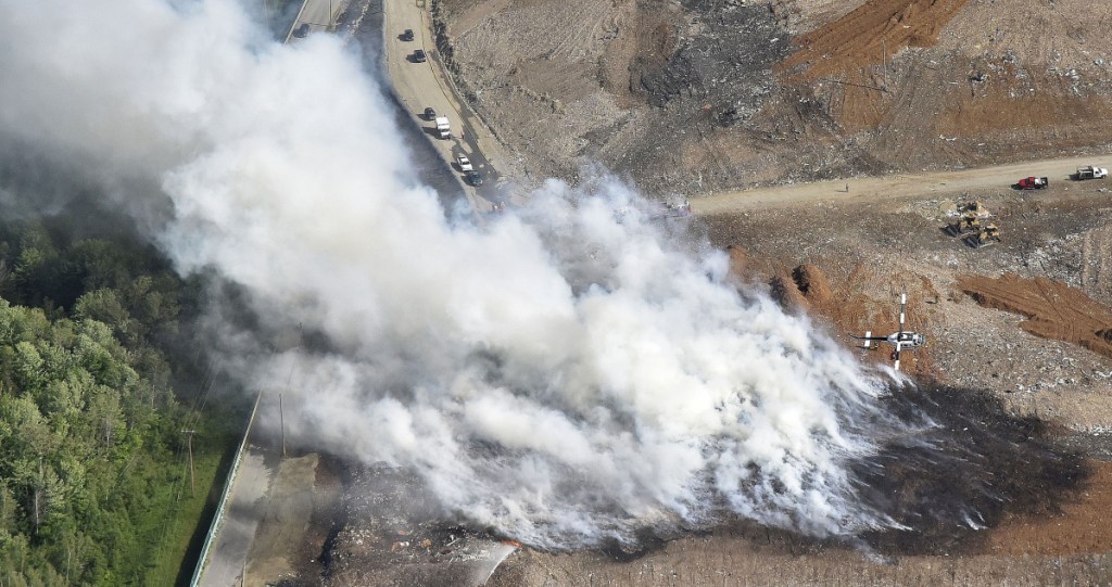 A Maine Forestry department helicopter finishes a pass dropping water Tuesday on a smoky fire burning at the Waste Management Crossroads Landfill in Norridgewock.