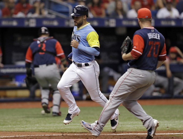 Tampa Bay's Kevin Kiermaier scores on a wild pitch by Boston Red Sox relief pitcher Ryan Brasier, right, as catcher Sandy Leon chases the ball during the Rays' 5-1 victory over Boston on Saturday evening in St. Petersburg, Florida.