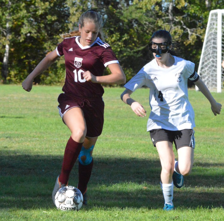 Richmond's Bry Shea (10) dribbles the ball down the sidelines as St. Dominic's Raegan Hachey pursues Thursday in Richmond.