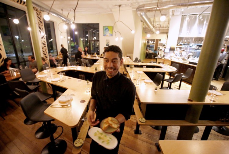 Server John Floyd carries dishes down Lio's long center aisle.