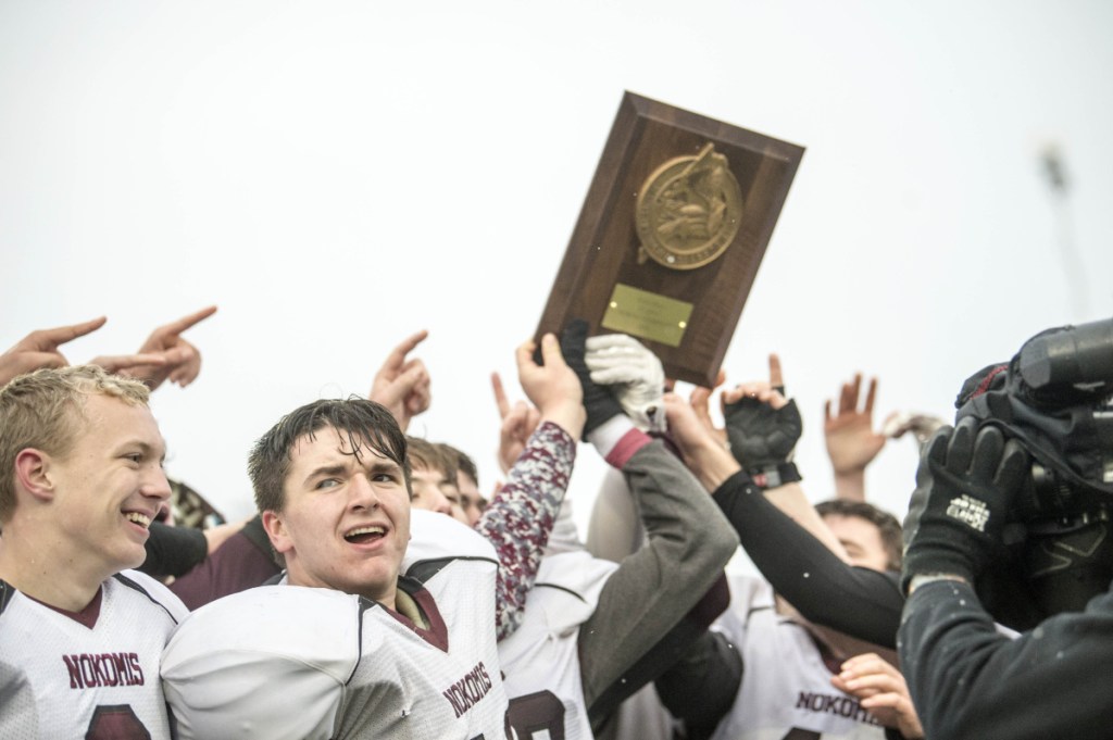 Staff photo by Michael G. Seamans 
 The Nokomis football team holds up the Class C North championship trophy after defeating Hermon on Saturday at Hampden Academy.