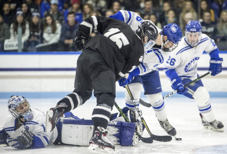 Colby College goalie Andrew Tucci (1) lies flat on his stomach as Bowdoin College's Thomas Dunleavy (15) looks to score with Colby's Austen Halpin (6) defending during a game at Alfond Rink in Waterville earlier this season.
