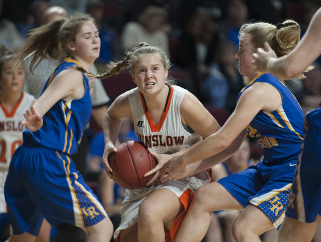 Seeking an opening: Winslow's Silver Clukey splits Lake Region defenders Rachel Shanks, left, and Shauna Hancock on her way to the basket during the Class B state championship game last season at the Cross Insurance Center in Bangor.