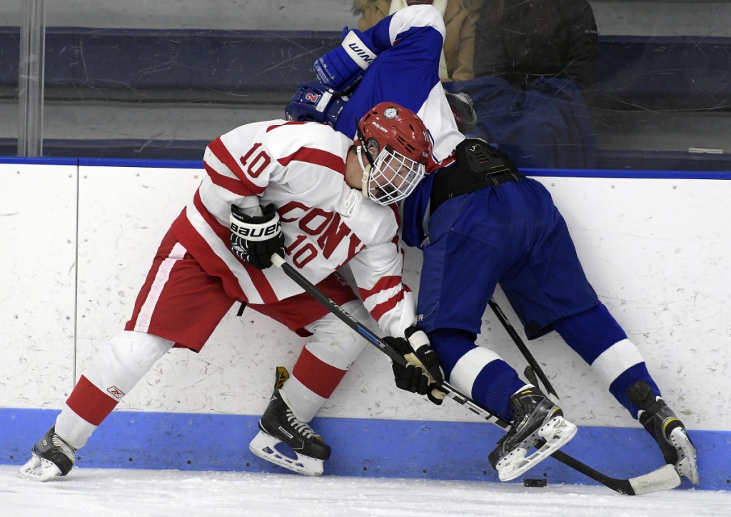 Cony's Michael Boivin, left, reaches for the puck under Lisbon/Mt. Ararat/Morse defenseman Noah Magda during a Class A North game last season in Hallowell.