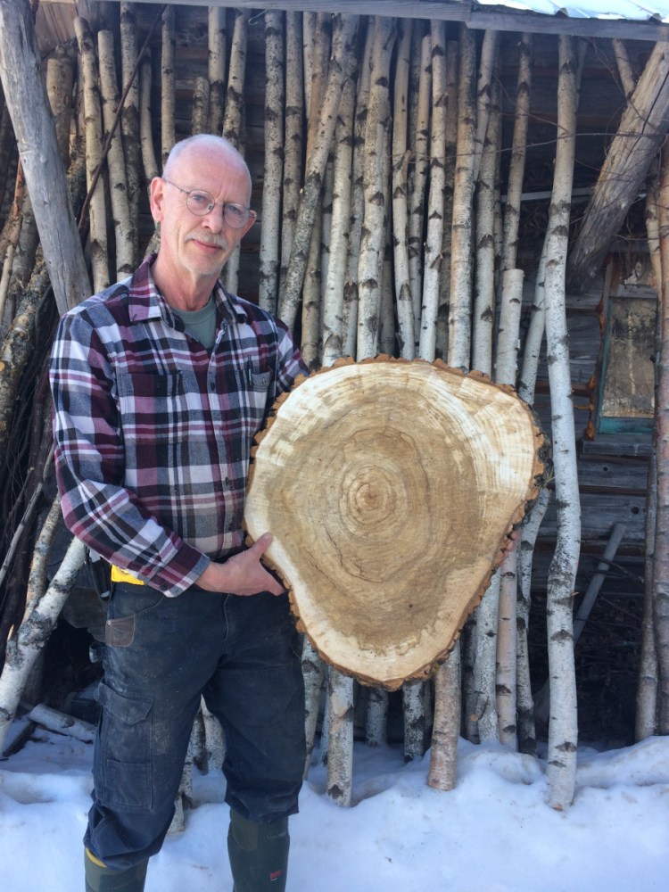 Lifelong Jackman resident Rene Guay holds a kiln-dried Balm of Gilead slice that will be used as the top of an end table. Guay said his online wood product business, Spirit of the Woods, has been negatively impacted by Central Maine Power Co.'s unreliable service in the area, which leads to frequent internet outages and has caused delays to the kiln-drying process. Guay said he has lost thousands of dollars in revenue over the last several years as a result.