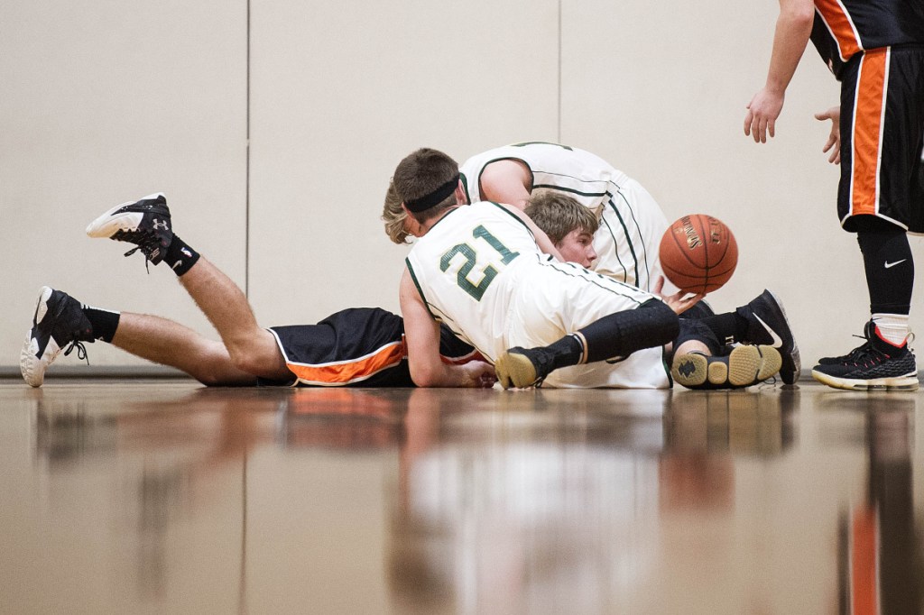 Forest Hills' Dalton Gregoire, center, passes the ball after fighting for it with Rangeley's Callahan Crosby (21) and Nolan Boone, back, on Saturday at Cony High School in Augusta.