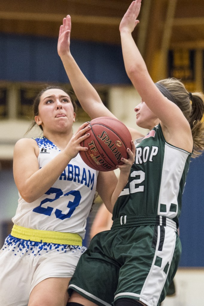 Mt Abram's Summer Ross (23) draws the foul from Winthrop's Layne Audet in the first half of a game last season in Salem. Ross scored her 1,000th career point Wednesday against Madison.