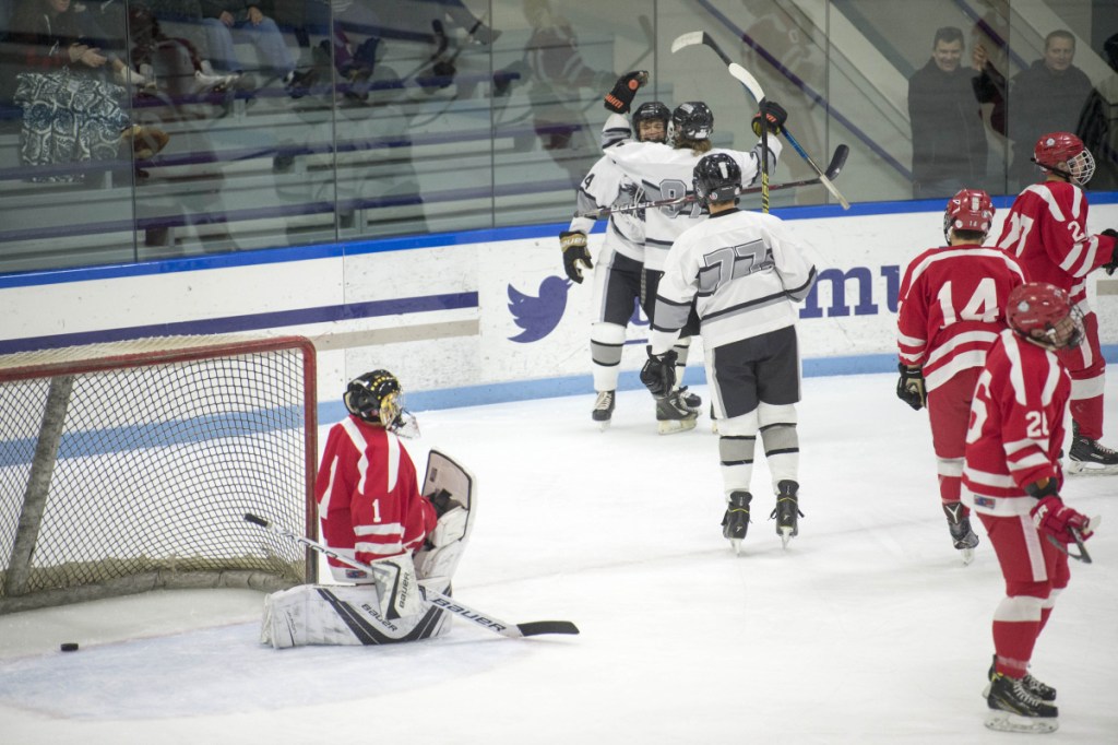 Kennebec's Hunter Brown, facing, celebrates a first-period goal with teammates Tommy Tibbetts and Brandon Bearce as Cony  goalie Matty Shea takes a knee Wednesday at Colby College in Waterville.