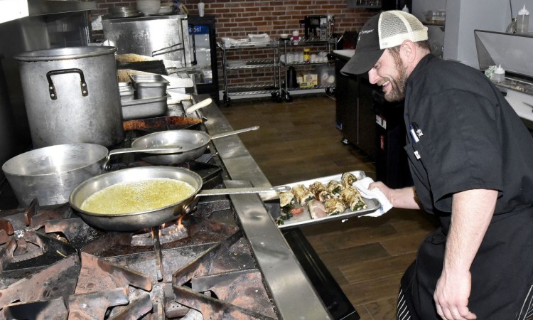 Opa restaurant head chef Joe Kenny places stuffed chicken in an oven Tuesday at the Greek restaurant on Main Street in Waterville.