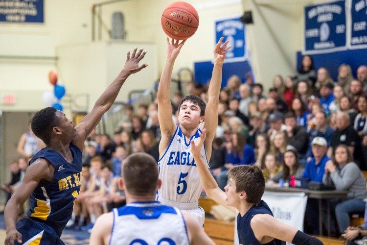 Erskine's Caden Turcotte (5) takes a shot as Mt. Blue's James Anderson, left, and Jacob Farhnam defend during a Class A North game Tuesday night in South China.