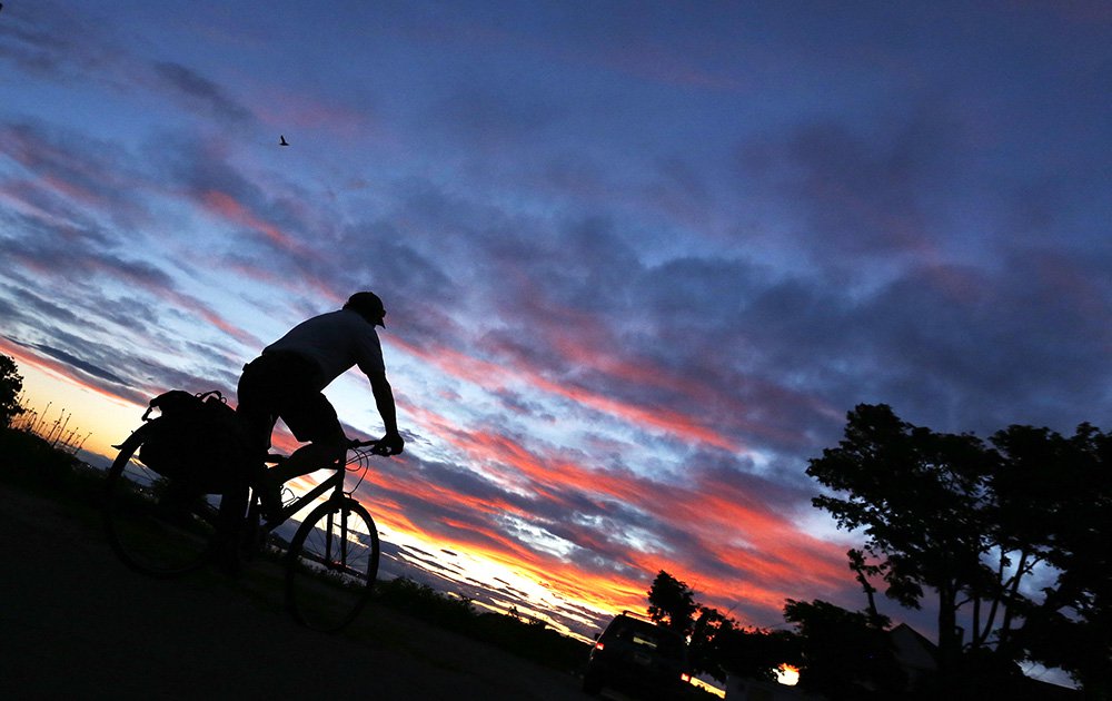 Walter Reiter rides his bike to a lookout spot on Island Avenue on Peaks Island Wednesday to catch the last light of the sunset on summer solstice. Staff photo by Ben McCanna