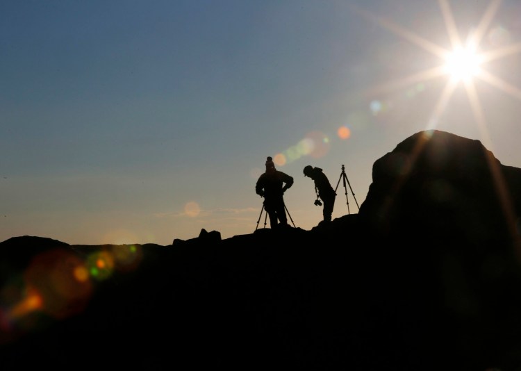 Anne Postpoole, right, and her husband, Matt, of South Berwick, set up their tripods at Sohier Park in York before capturing the rising moon over Nubble Light on March 20.