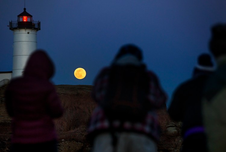 Photographers gather on the rocks at Sohier Park in York as they aim to capture the moonrise over Nubble Light.