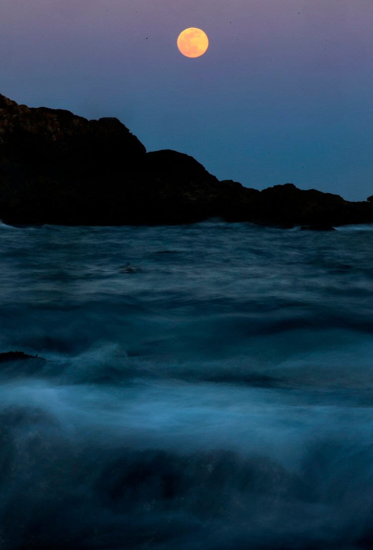 A full moon rises from the horizon, seen from Sohier Park in York on March 20.