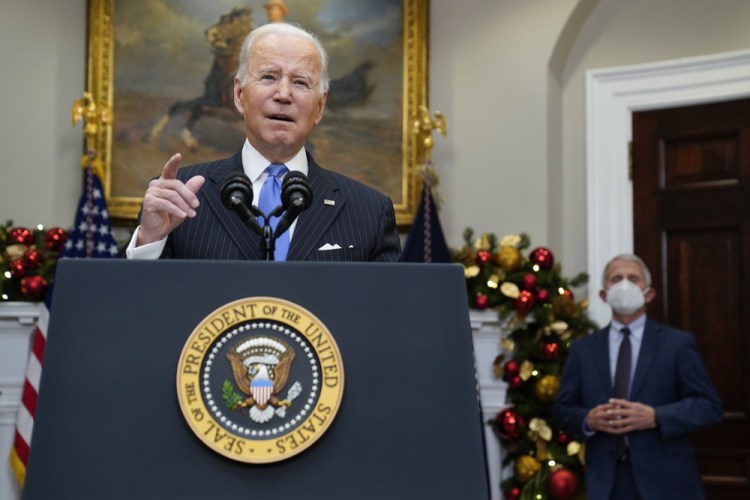 President Biden speaks about the COVID-19 variant omicron in the Roosevelt Room of the White House on Monday in Washington, as Dr. Anthony Fauci, director of the National Institute of Allergy and Infectious Diseases, listens. 