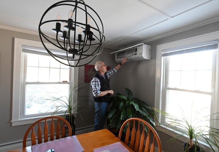 Steve Kahl, a professor at Thomas College and host of the "Power for the People" show on WERU Community Radio, with one of two heat pumps last week at his energy-efficient house in Waterville. Kahl has also installed expanding foam insulation on the walls of his basement and attic crawl space, and found energy savings by enrolling in a community solar program.