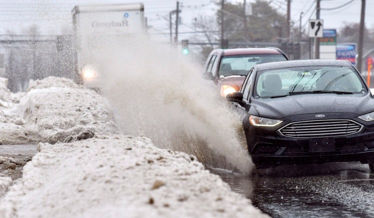 A car splashes through a puddle Tuesday while heading heading west on Western Avenue in Augusta. Rain and warm temperatures causing snow melt led to large puddles in some areas. 