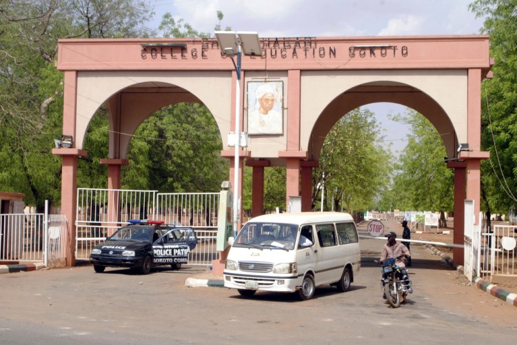 A man rides a motorbike taxi past police vehicles at the entrance of Shehu Shagari College of Education in Sokoto, Nigeria, on Friday, May 13, 2022. A student was beaten and burnt to death Thursday by fellow students at the northwestern Nigeria school after she was accused of making a blasphemous social media post, witnesses and police said. (AP Photo/Olu Akinrele)