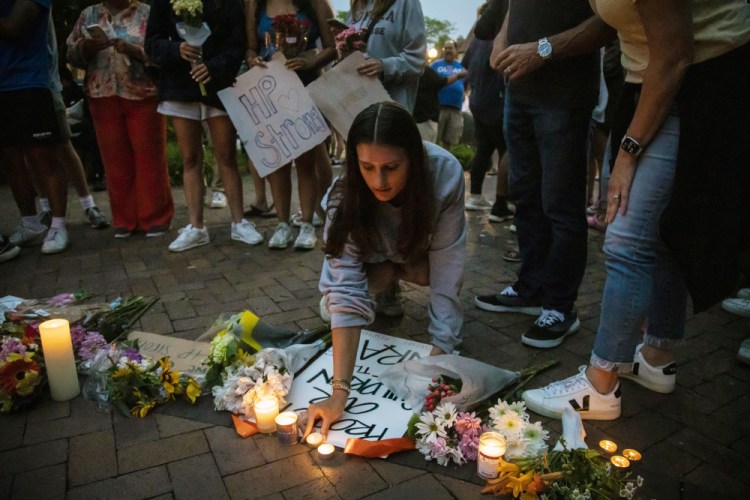 Dozens of mourners gather for a vigil near Central Avenue and St. Johns Avenue in downtown Highland Park, one day after a gunman killed at least seven people and wounded dozens more .