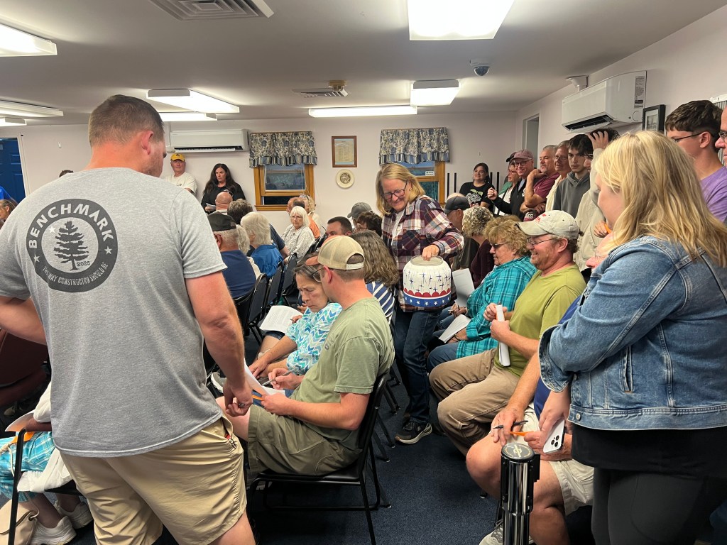 China Deputy Clerk Julie Finley steps through a crowded row of China residents, holding out a plastic bin to collect votes on discontinuing a public easement.